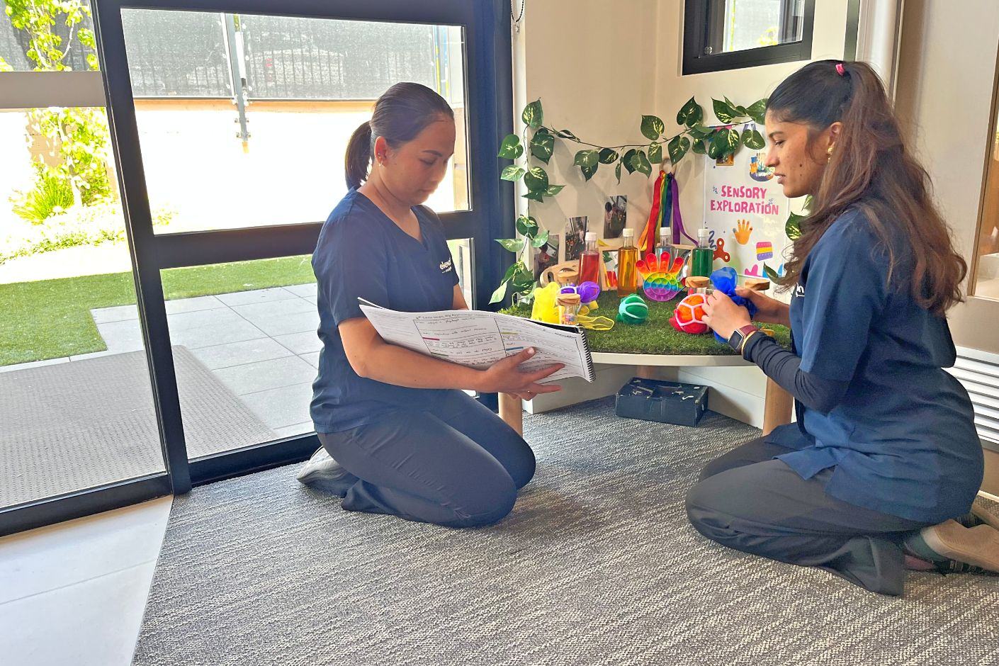 Two Elevation Early Learning educators planning a sensory exploration activity together